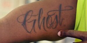Ghost tattoo on arm, inked in cursive style. Tattoo of the word "Ghost" on arm in cursive ink.