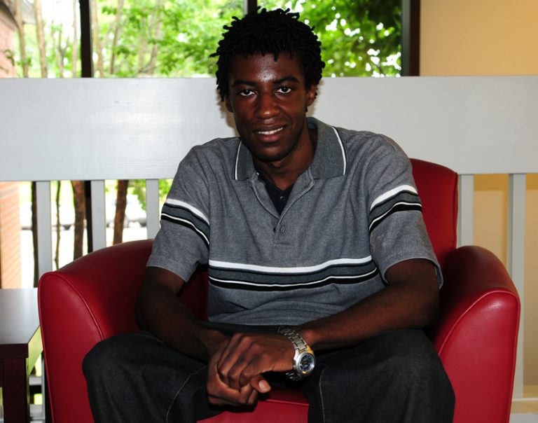 Student sitting confidently in a red chair at eCorsair, Pensacola State College.