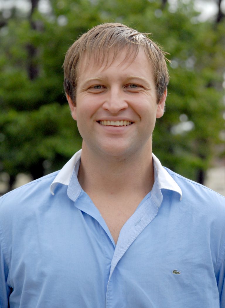 Student smiling outdoors, learning money-saving tips for college success.