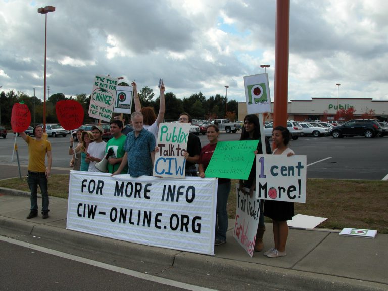 Group of protesters holding signs outside Publix advocating for farmworker rights.