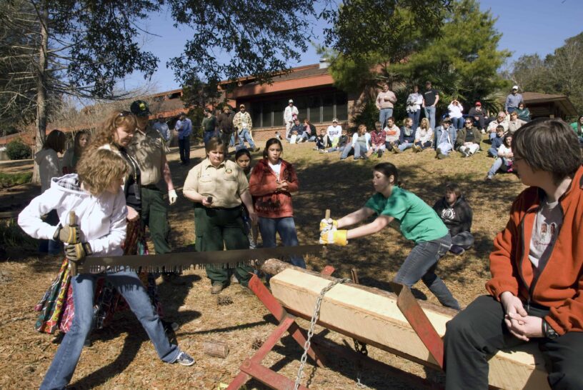 Lumberjack competition at the festival with participants chopping wood outdoors.