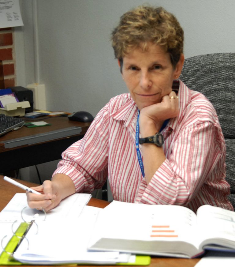 Woman studying at desk with open books, focused on learning.