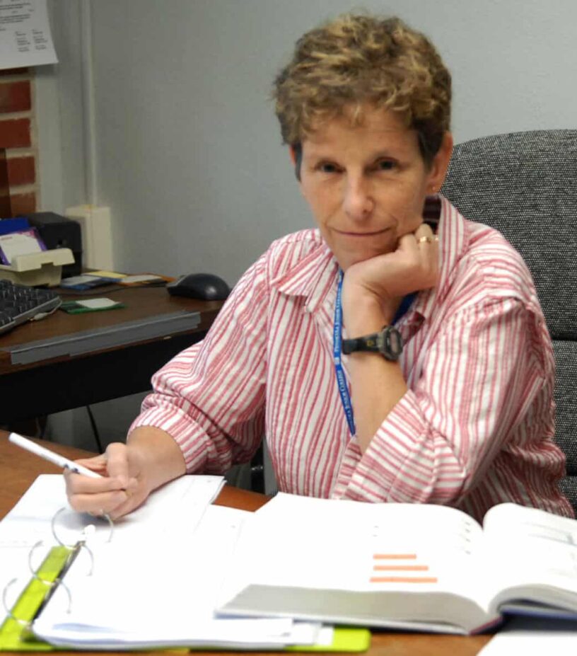 Woman studying at desk with open books, focused on learning.