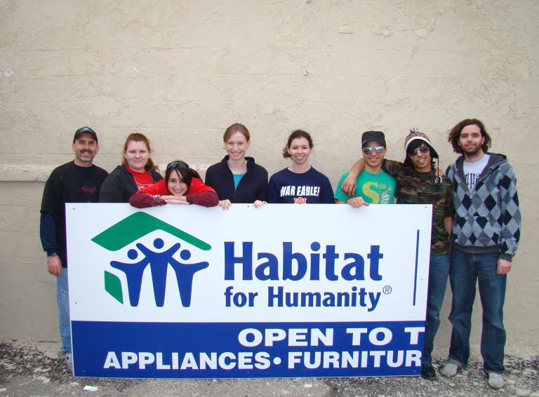 Volunteer team holding Habitat for Humanity sign.