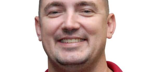 Smiling man in red shirt representing eCorsair at Pensacola State College.