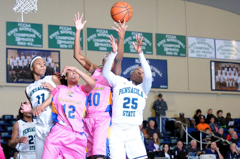 Female basketball players competing in a game at Pensacola State College gymnasium.