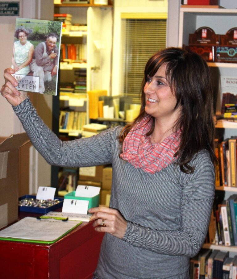 Woman holding Hurricane Review magazine at bookstore event.