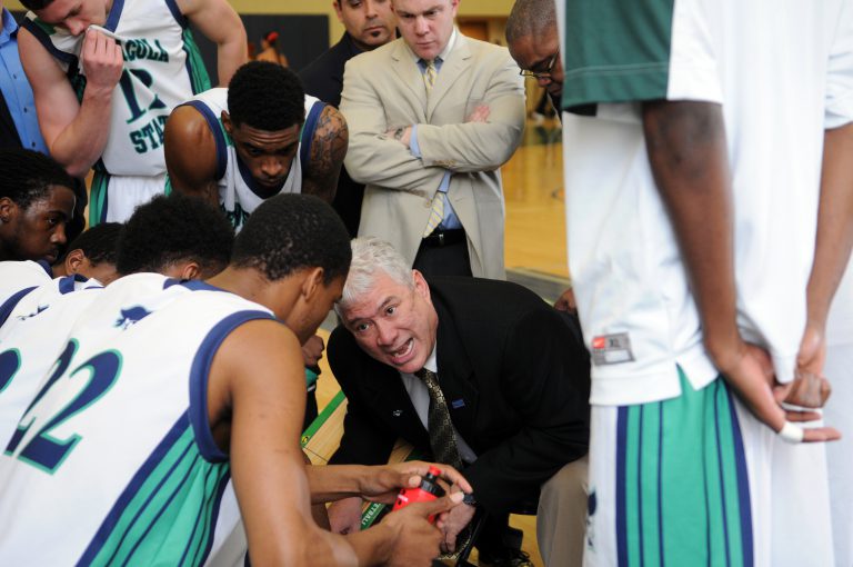 Pirates basketball team coaching during timeout at a game.