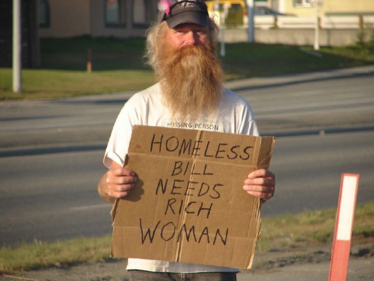 Man holding a cardboard sign about homelessness during a city council discussion.