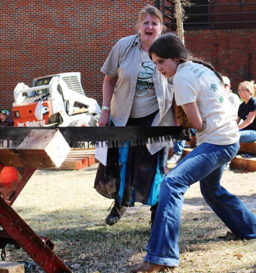 Lumberjack Festival Woodcutting Competition Women participating in lumberjack festival woodcutting contest outdoors.