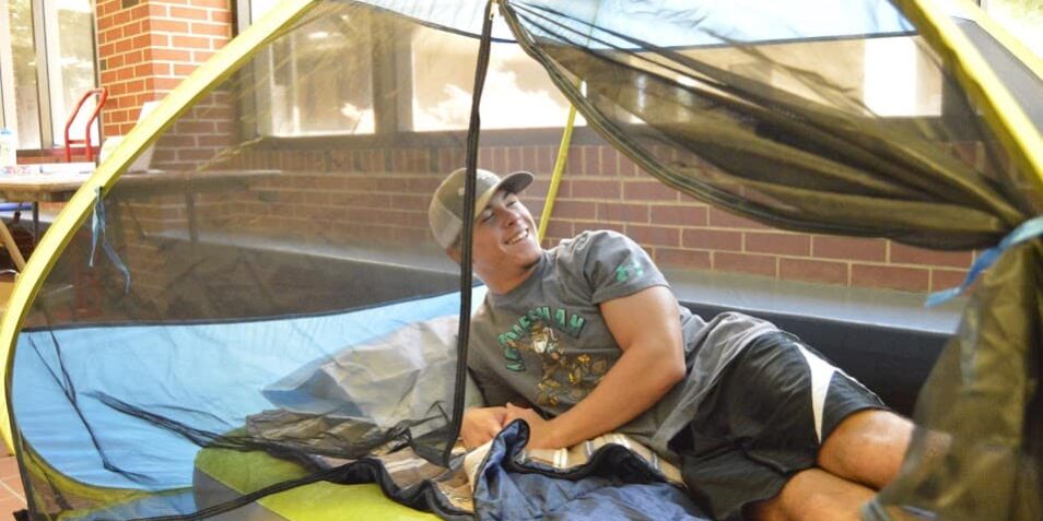 Student relaxing inside a tent during Stress Less Week activities at Pensacola State College.
