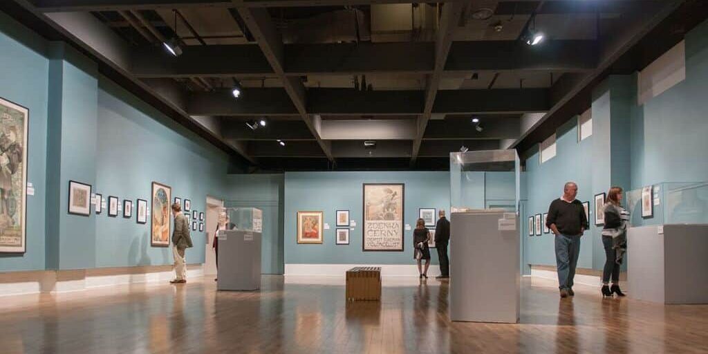 Visitors viewing the Mucha art exhibit at Pensacola Museum of Art.