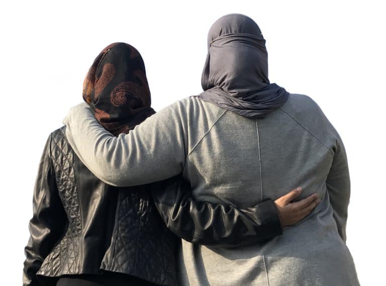 Two women, one wearing a hijab, embracing to show support against Islamophobia in America.
