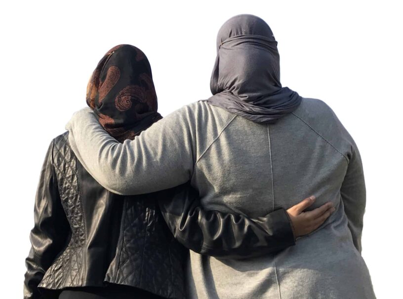Two women, one wearing a hijab, embracing to show support against Islamophobia in America.