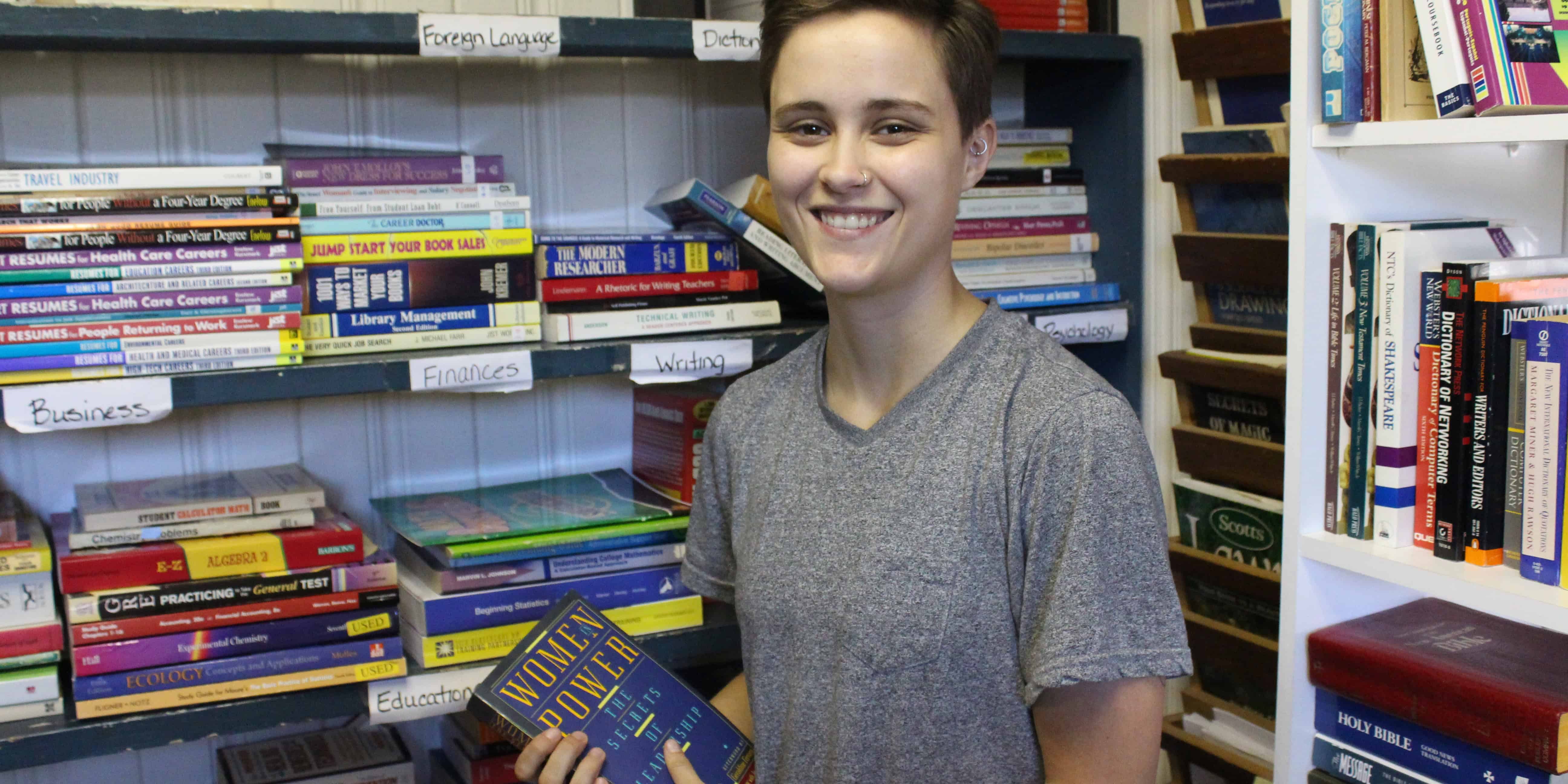 Student at eCorsair library holding a book on women in leadership.