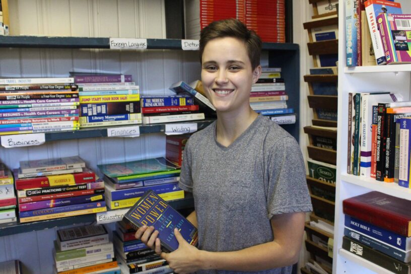 Student at eCorsair library holding a book on women in leadership.