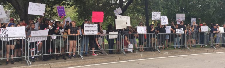 Protesters holding signs in a peaceful demonstration about healing and tradition.