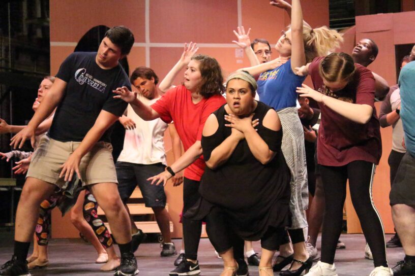Performers act out a scene from the Addams Family musical on stage.