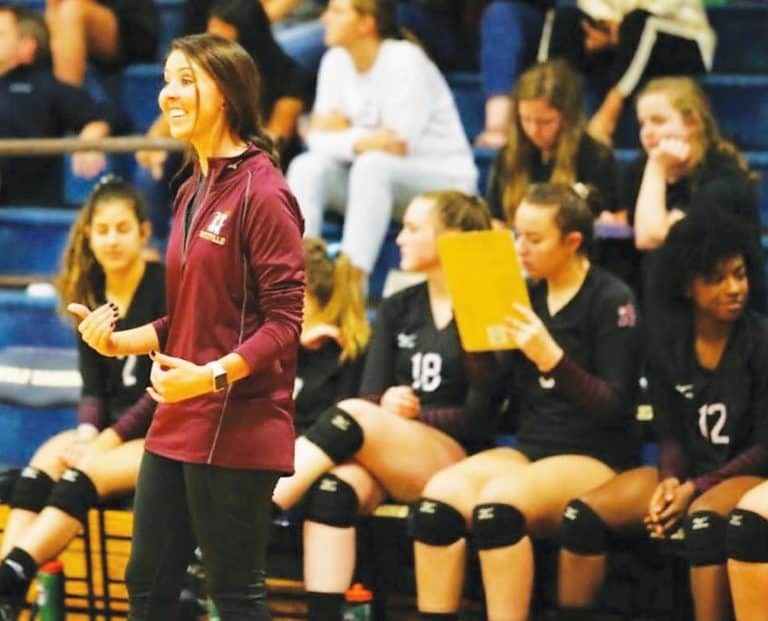 Female volleyball coach speaking to team during match at Pensacola State College.