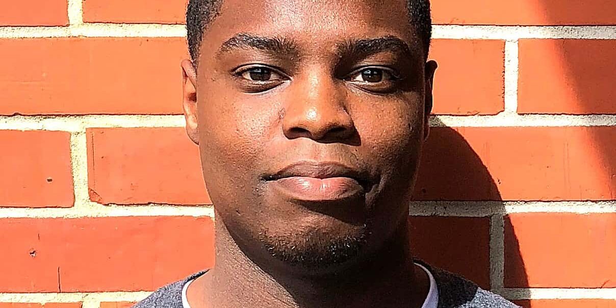 Young man standing against brick wall, promoting softball injury awareness and pre-med education.