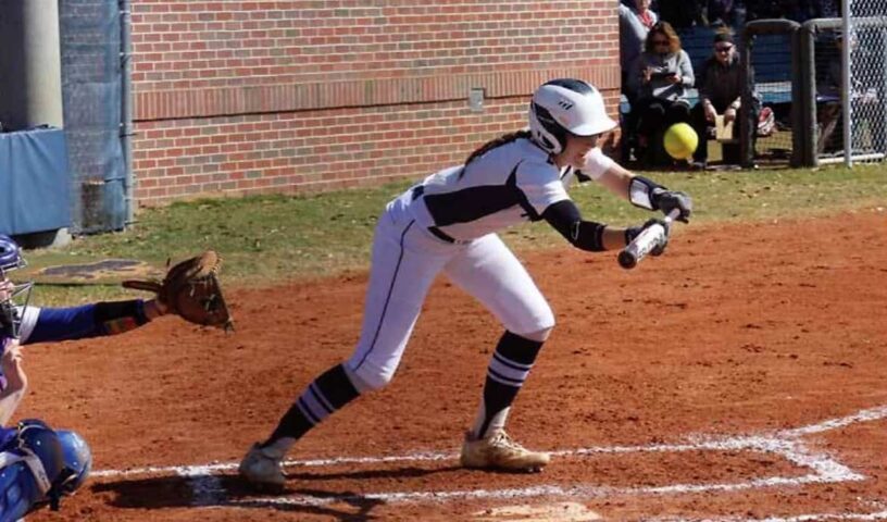 Female baseball player sliding into home plate during a game.