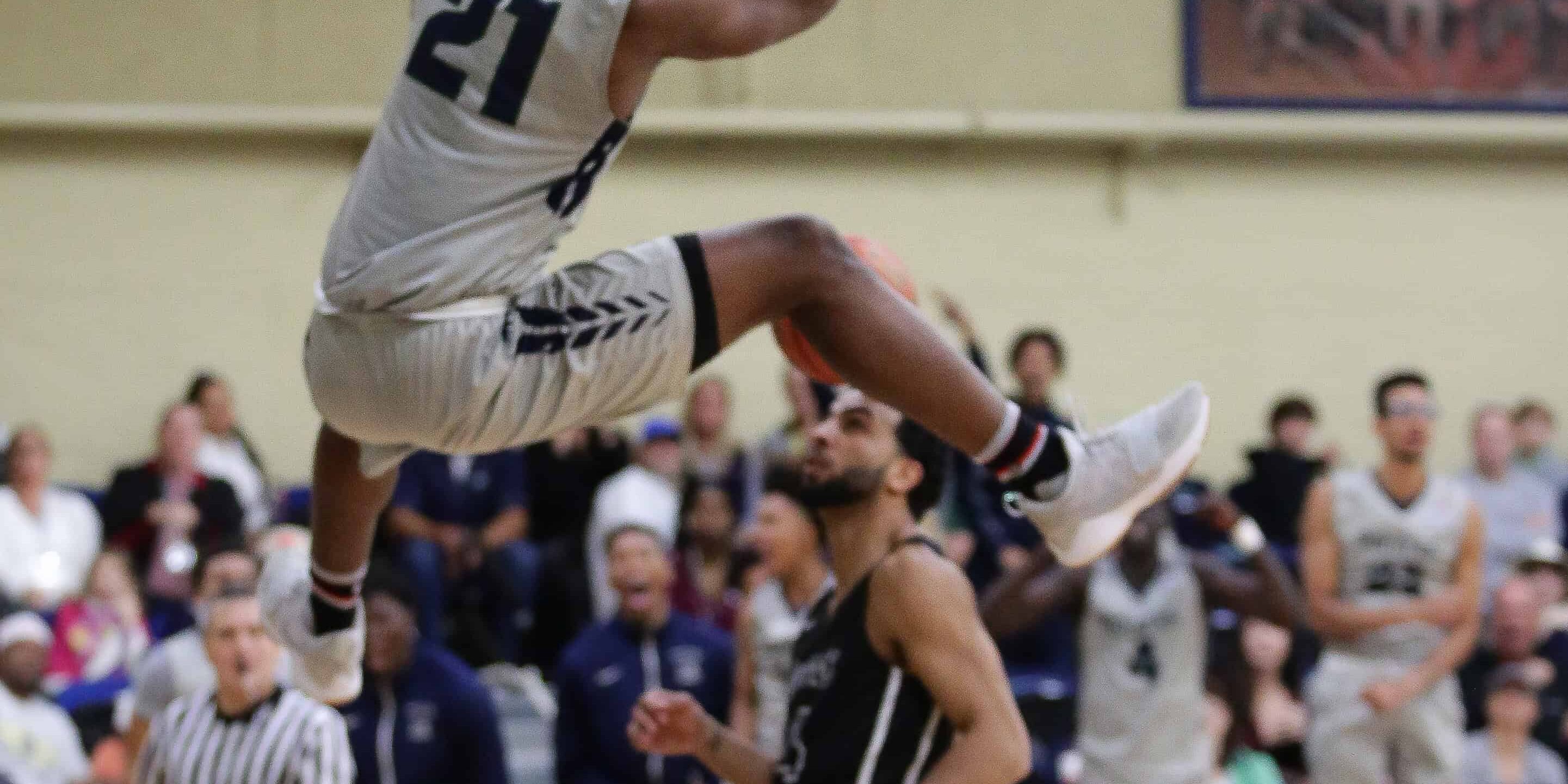 Athlete Willesley Butler soars above opponents for a powerful dunk in the basketball game.