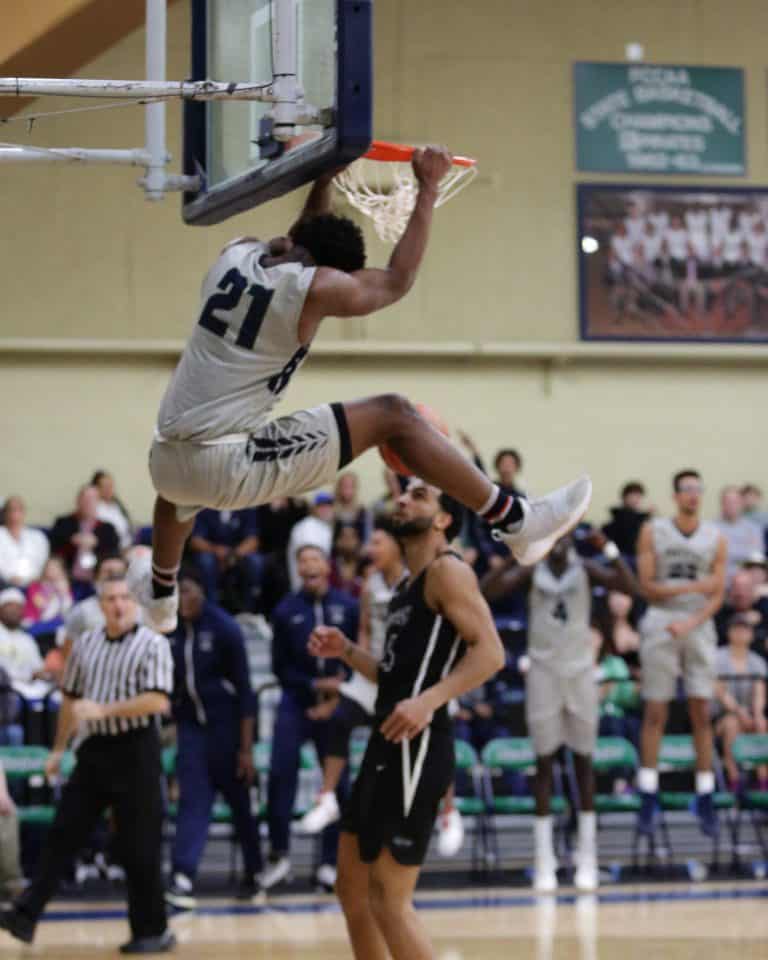 Athlete Willesley Butler soars above opponents for a powerful dunk in the basketball game.