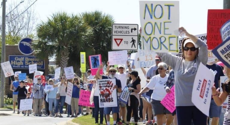 Protesters holding signs during March for Our Lives rally advocating gun control.