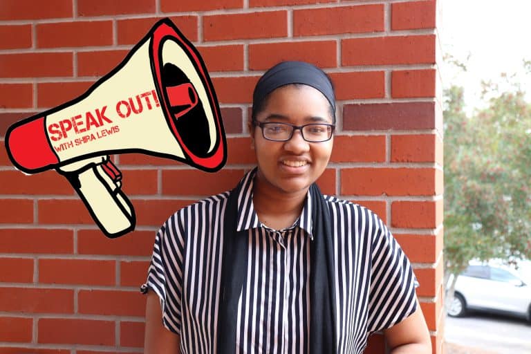 Student holding a megaphone with "Speak Out!" message outside on campus.