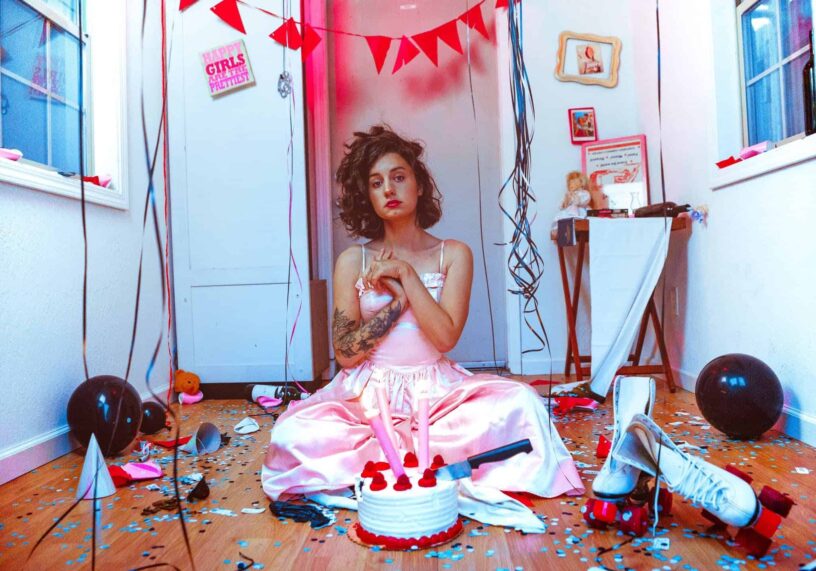 Celebration with Cake and Balloons Young woman in pink dress sitting with cake, balloons, and party decorations.