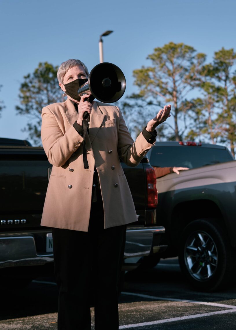 Campus student using a megaphone outdoors at eCorsair event. Student with a megaphone speaking at eCorsair event on campus.