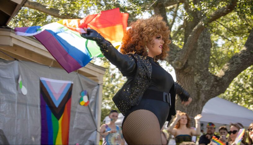 Pride Celebration with LGBTQ+ Flag Woman waving rainbow pride flag at outdoor LGBTQ+ event.