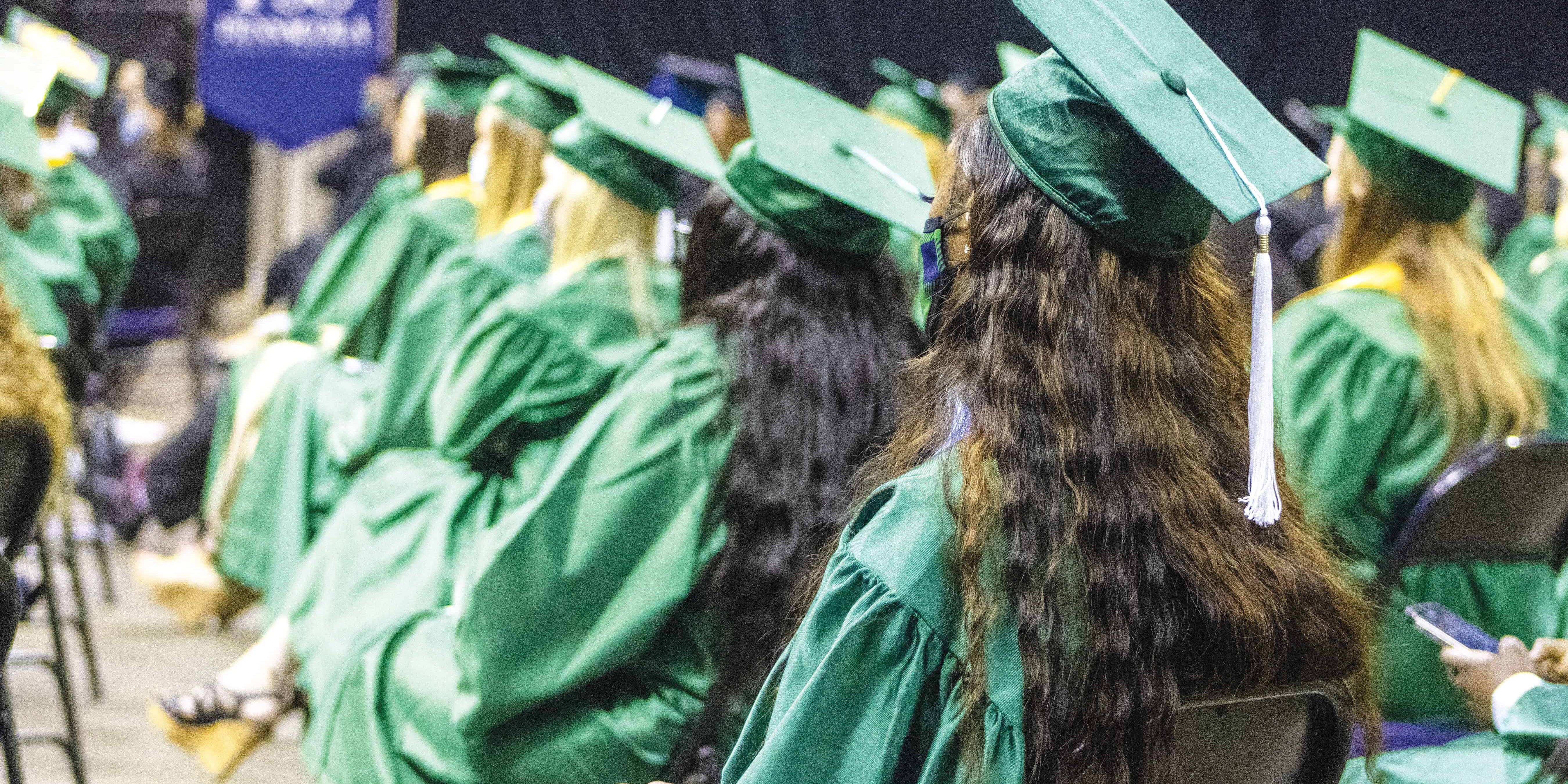 Students in green caps and gowns at eCorsair graduation event.
