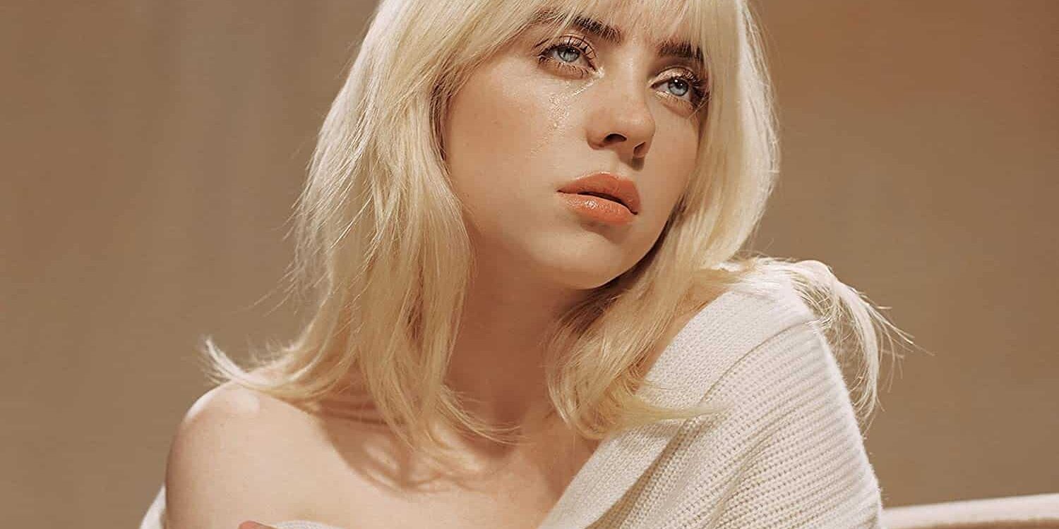 Close-up of a woman with blonde hair and a white sweater, looking contemplative.