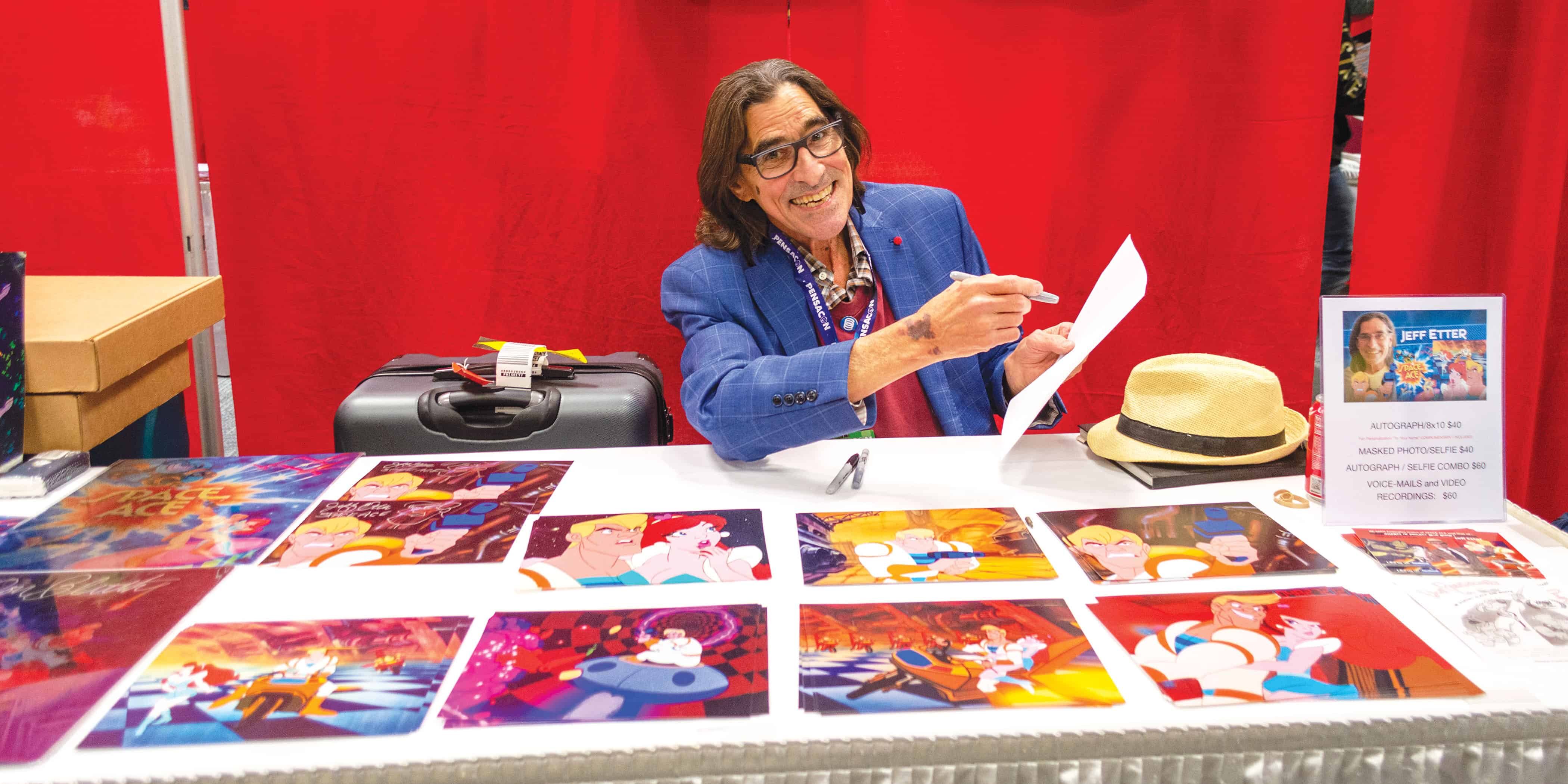 Woman at eCorsair booth showcasing student artwork and creative projects.