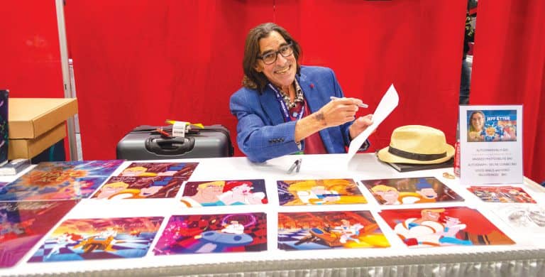 Woman at eCorsair booth showcasing student artwork and creative projects.