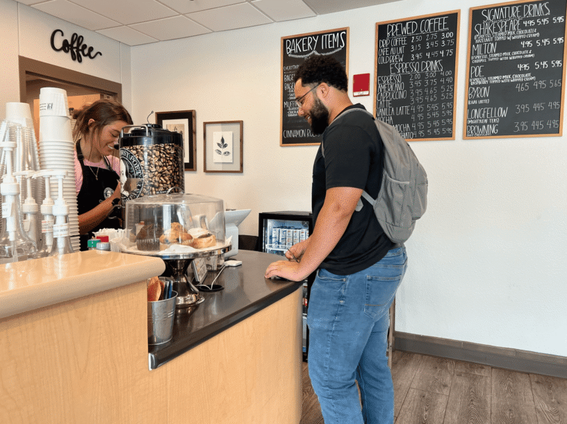 Student paying with card at coffee shop counter for eCorsair.