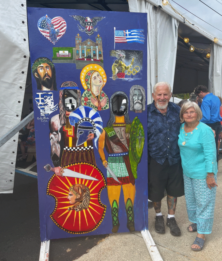 Colorful Greek festival display with cultural symbols and two smiling attendees.