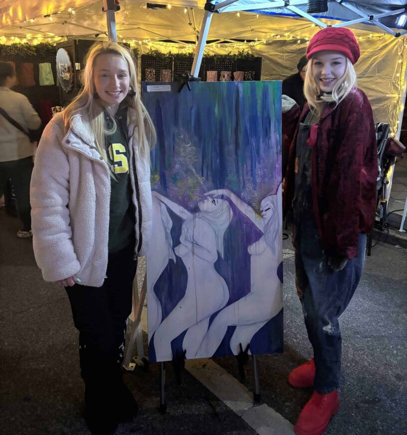 Pensacola Native Art at Gallery Night Two young women showcasing a colorful abstract painting at Pensacola's Gallery Night event.