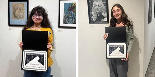 Student art award winners holding certificates at the eCorsair art exhibition.