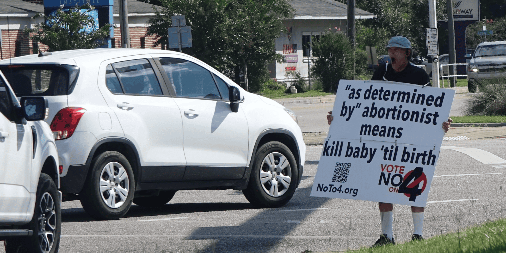 Pro-Life Protester at Florida Intersection Person holding anti-abortion sign near traffic in Florida.