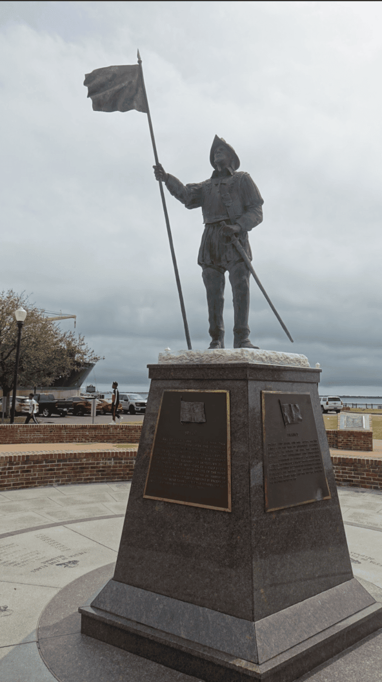 Statue of a historical figure holding a flag in downtown area.