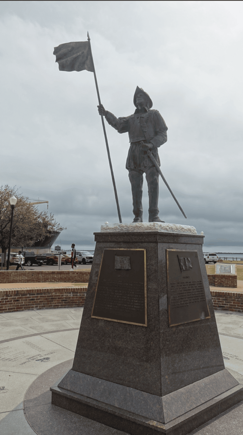 Statue of a historical figure holding a flag in downtown area.