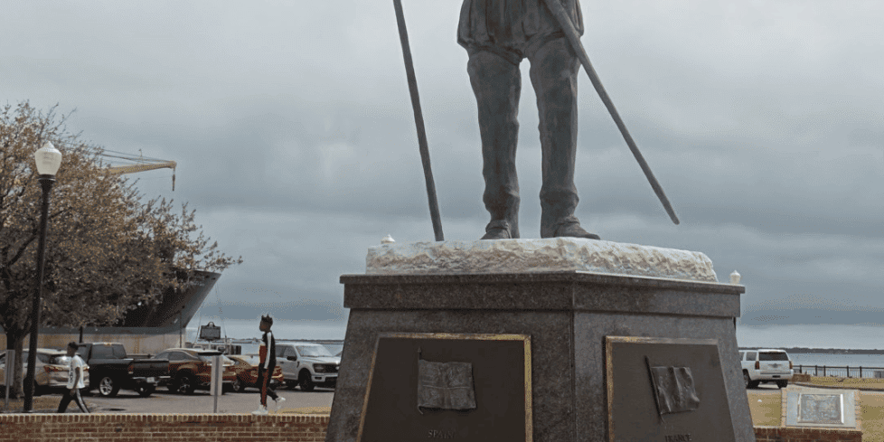 Statue of a historical figure holding a flag in downtown area.