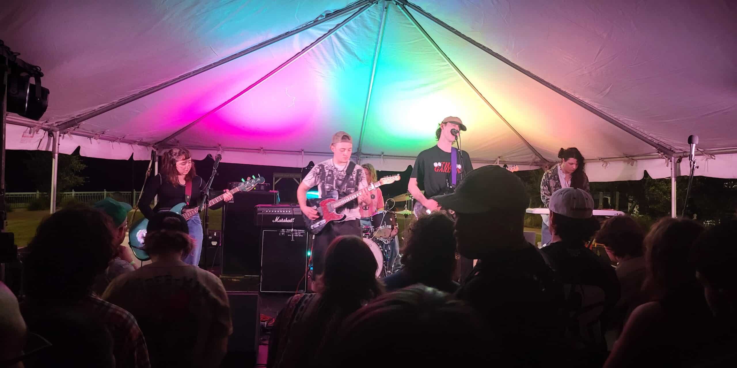 Keep It Movin’ Night Moves Festival Live band performing at Pensacola’s Night Moves Festival under colorful tent lighting.