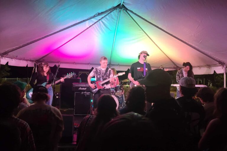 Live band performing at Pensacola’s Night Moves Festival under colorful tent lighting.
